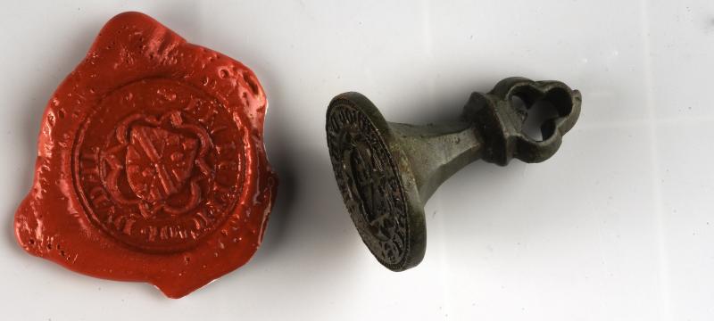 L'image montre une sceau de matrice en bronze avec un cachet de cire. Cet objet a été retrouvé lors des fouilles archéologiques programmées réalisé par l'inrap au Château du Guildo.